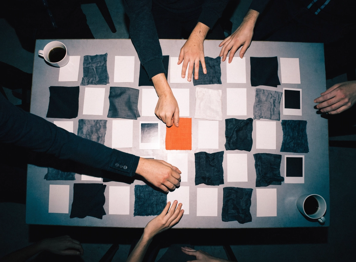 Team sorting fabric swatches on a planning table, one orange swatch among grey